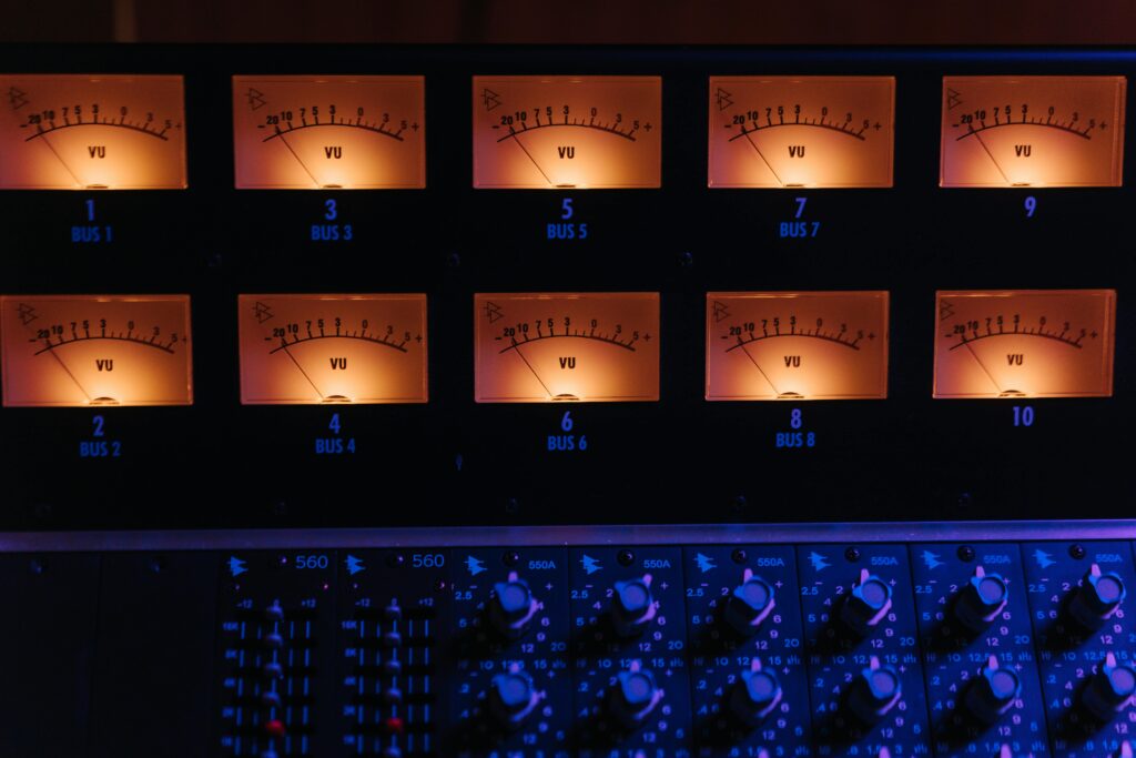 Close-up of illuminated VU meters on a professional audio mixing console in a music studio.